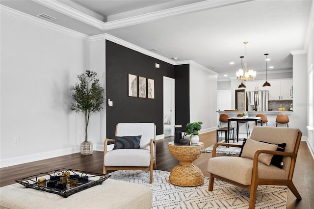 living area with ornamental molding, wood finished floors, visible vents, and an inviting chandelier