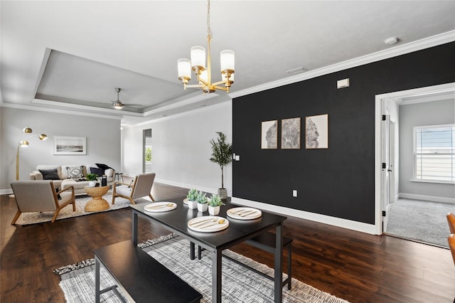 dining area featuring crown molding, a tray ceiling, dark wood finished floors, and baseboards