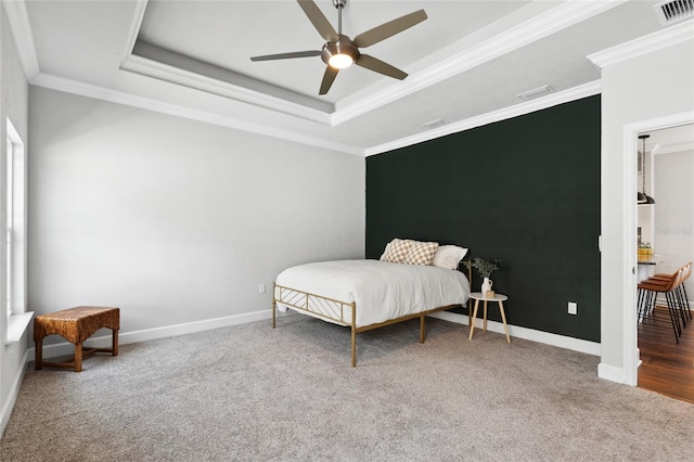 carpeted bedroom with baseboards, visible vents, and a raised ceiling