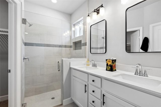 bathroom featuring a sink, a shower stall, and double vanity