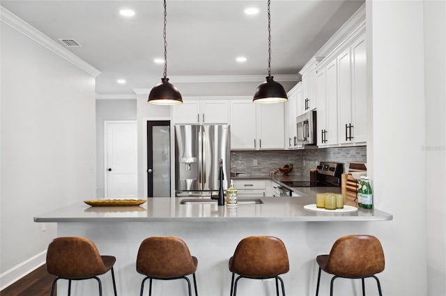 kitchen featuring appliances with stainless steel finishes, a sink, crown molding, a kitchen bar, and backsplash