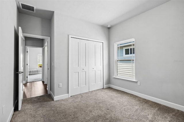 unfurnished bedroom with carpet floors, baseboards, visible vents, and a closet