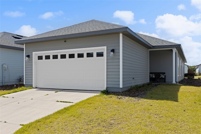 view of side of property with a yard, a detached garage, and roof with shingles