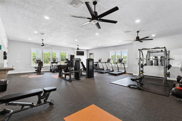 exercise room with plenty of natural light, baseboards, visible vents, and a textured ceiling