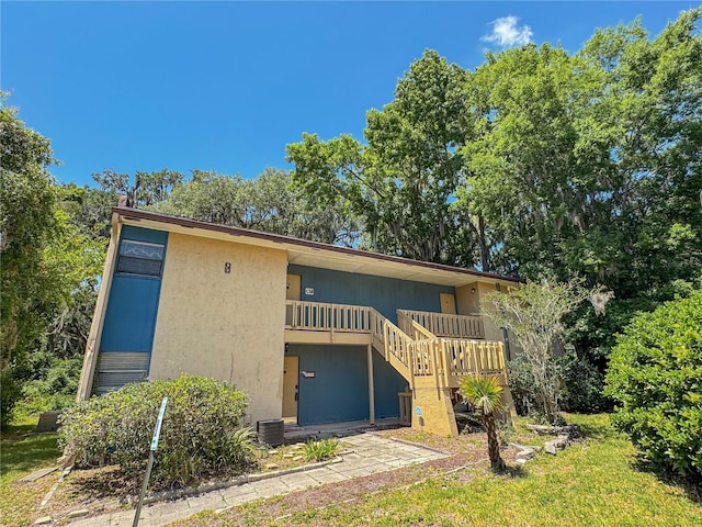 rear view of property with stairs and stucco siding