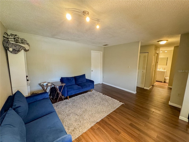 living area featuring wood finished floors, baseboards, and a textured ceiling