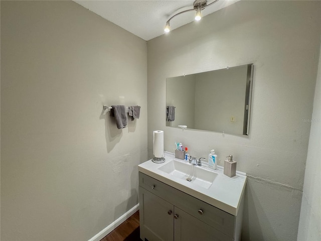 bathroom with baseboards, wood finished floors, and vanity