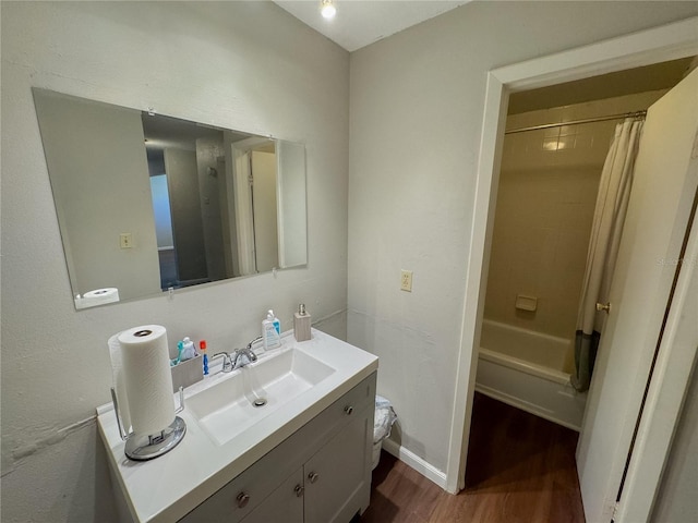 full bathroom with baseboards, shower / bath combo with shower curtain, wood finished floors, and vanity