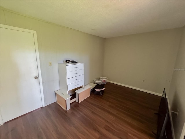 unfurnished bedroom with baseboards, dark wood-style flooring, and a textured ceiling