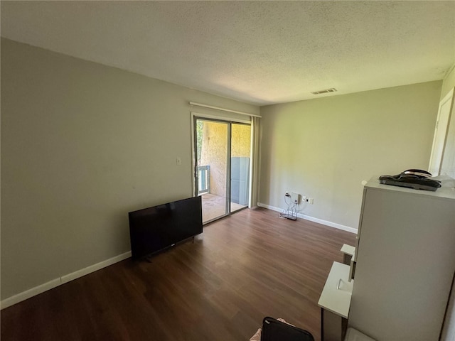 interior space featuring visible vents, baseboards, a textured ceiling, and wood finished floors