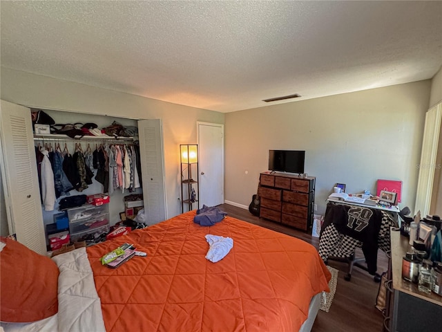 bedroom with a closet, visible vents, a textured ceiling, and wood finished floors