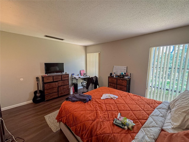 bedroom with visible vents, baseboards, a textured ceiling, and dark wood finished floors