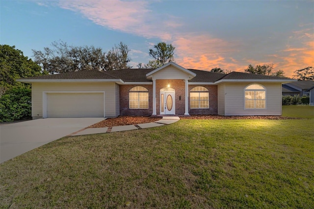 single story home with a garage, a front yard, concrete driveway, and brick siding