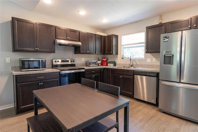 2306 NW 121st Ave, Gainesville, FL 32609 - kitchen with a sink, appliances with stainless steel finishes, under cabinet range hood, light wood-type flooring, and dark brown cabinets