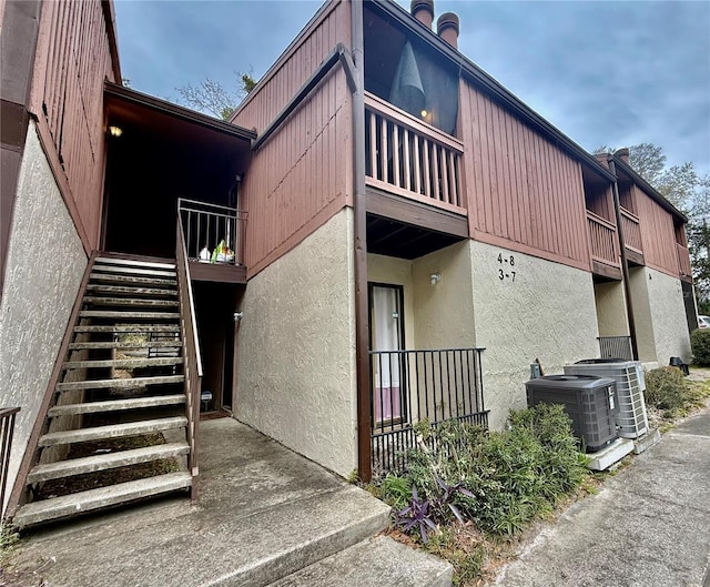 view of property with central air condition unit and stairs