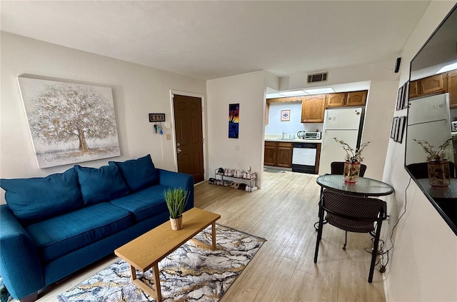 living area featuring a toaster, visible vents, and light wood-type flooring