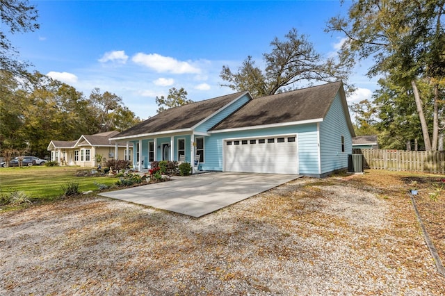 view of front of house featuring central air condition unit, concrete driveway, covered porch, fence, and a garage