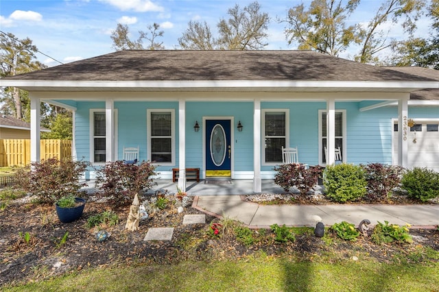 view of front facade with a porch, fence, and a shingled roof