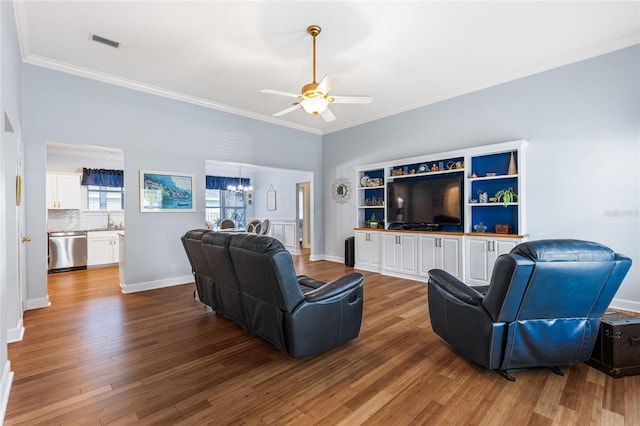 living area with crown molding, visible vents, and wood finished floors