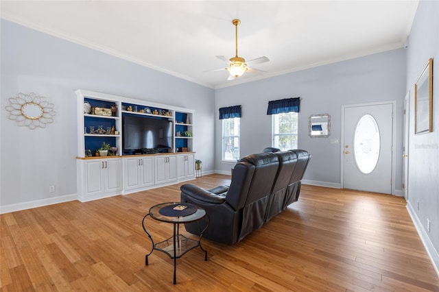 living area with light wood-style floors, baseboards, a ceiling fan, and crown molding