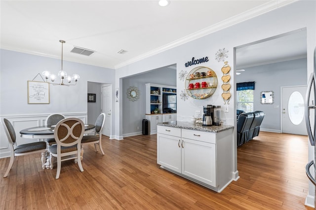 kitchen with light wood-style floors, visible vents, light stone counters, and white cabinetry