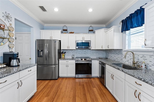 kitchen with visible vents, appliances with stainless steel finishes, ornamental molding, white cabinetry, and a sink