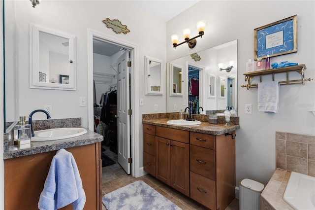 bathroom featuring tiled bath, a walk in closet, vanity, and tile patterned floors