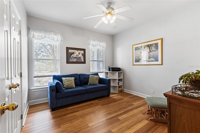 sitting room with a ceiling fan, baseboards, and wood finished floors