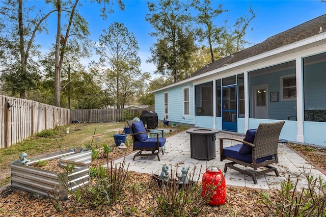 view of patio featuring a sunroom, a fenced backyard, a grill, and a fire pit