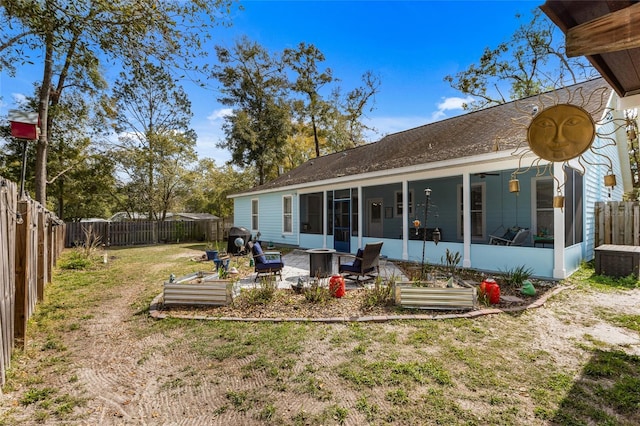 back of house featuring a sunroom, a fenced backyard, a yard, and a patio