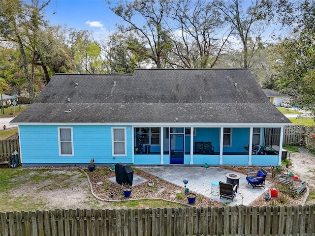 rear view of property featuring an outdoor fire pit, fence private yard, a sunroom, roof with shingles, and a patio area