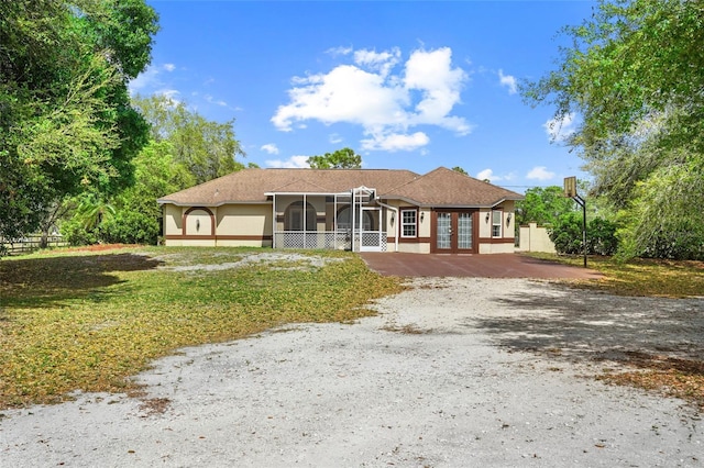 view of front of property featuring driveway, a sunroom, fence, and french doors