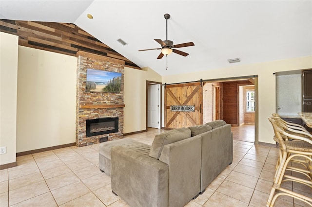 living room featuring light tile patterned floors, lofted ceiling, visible vents, a barn door, and ceiling fan