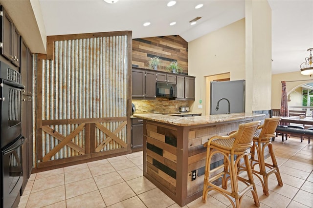 kitchen featuring light stone counters, light tile patterned floors, tasteful backsplash, high vaulted ceiling, and black appliances