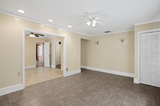 tiled empty room with ornamental molding, visible vents, ceiling fan, and baseboards