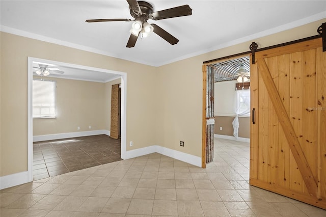 empty room featuring light tile patterned floors, a barn door, baseboards, and a healthy amount of sunlight