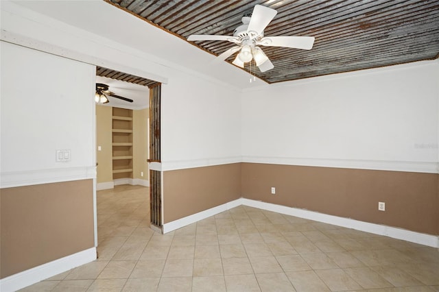 empty room with built in features, ceiling fan, baseboards, and light tile patterned floors