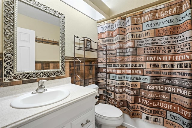 bathroom featuring a skylight, a shower with curtain, vanity, and toilet