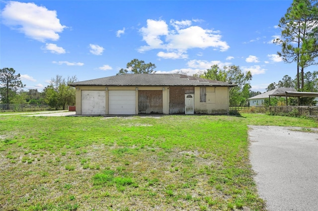 view of front facade with driveway, a front lawn, an attached garage, and fence