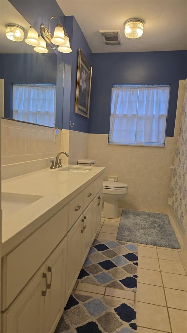 full bath with visible vents, toilet, vanity, tile patterned floors, and tile walls