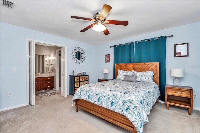 bedroom featuring visible vents, a ceiling fan, ensuite bath, baseboards, and light colored carpet