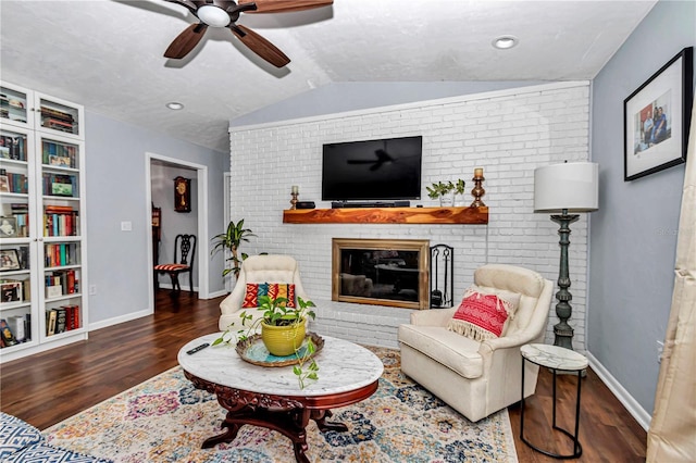 living room with ceiling fan, baseboards, vaulted ceiling, a fireplace, and wood finished floors