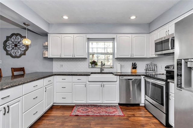 kitchen featuring a sink, white cabinetry, dark stone counters, appliances with stainless steel finishes, and dark wood-style flooring