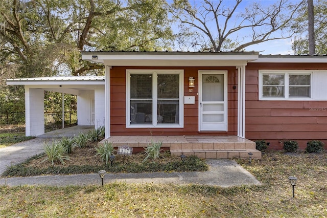 exterior space with metal roof, a carport, and driveway