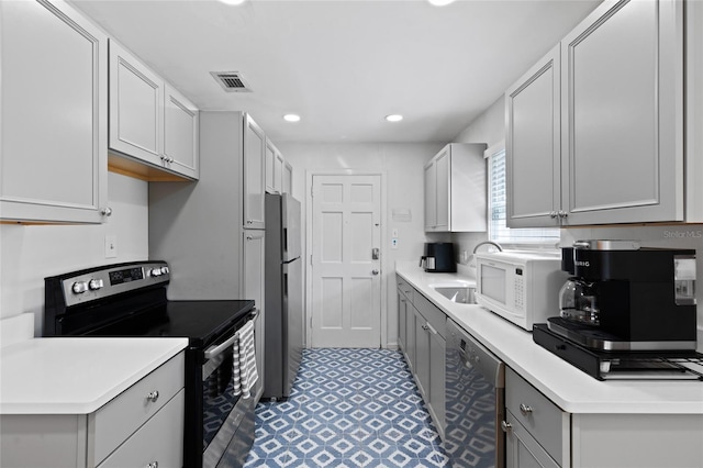 kitchen featuring visible vents, appliances with stainless steel finishes, light countertops, and gray cabinetry