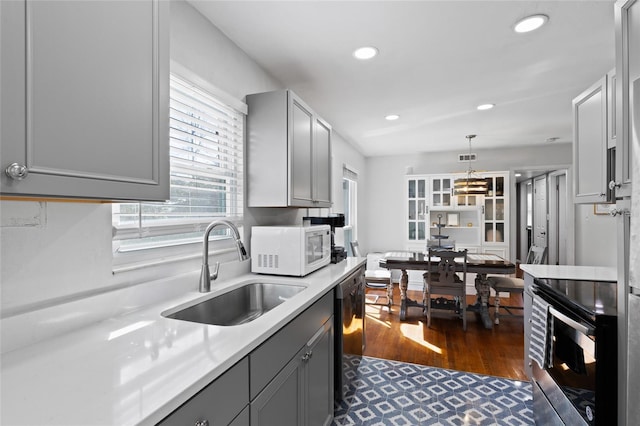 kitchen with gray cabinetry, a sink, stainless steel electric stove, white microwave, and dishwasher