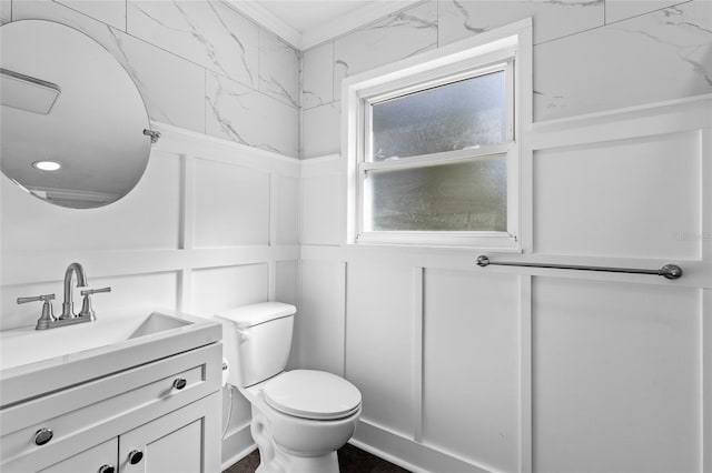 bathroom featuring toilet, vanity, and a decorative wall