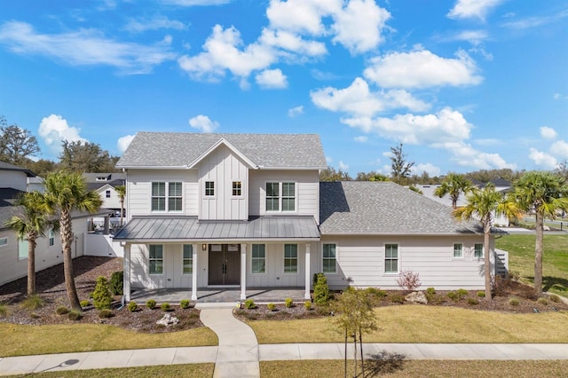 view of front of home featuring a front yard, roof with shingles, a standing seam roof, a porch, and board and batten siding