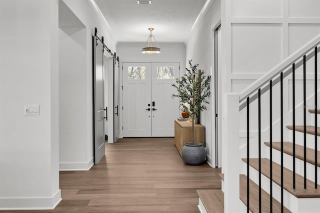 entryway featuring stairway, a barn door, baseboards, and wood finished floors