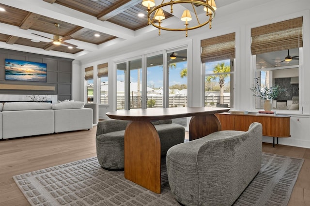 dining room featuring ceiling fan with notable chandelier, beamed ceiling, wood finished floors, and a healthy amount of sunlight